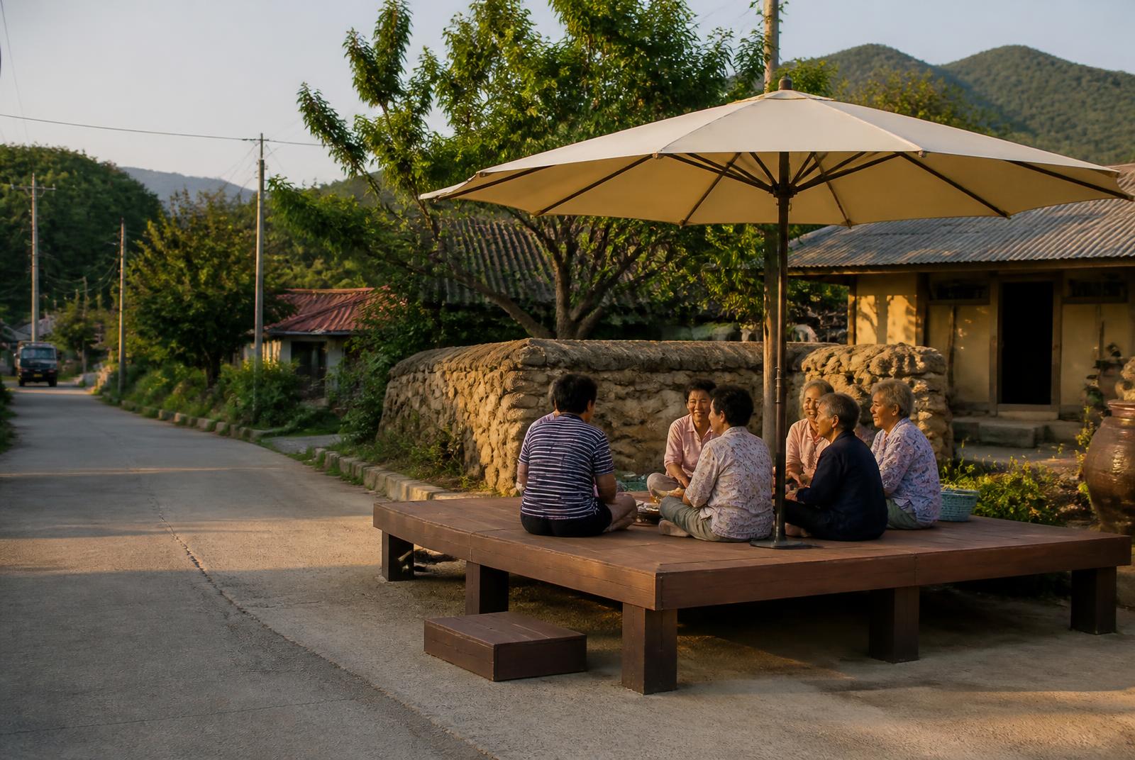 Villagers seated together on a completed pyeongsang platform under a shade umbrella